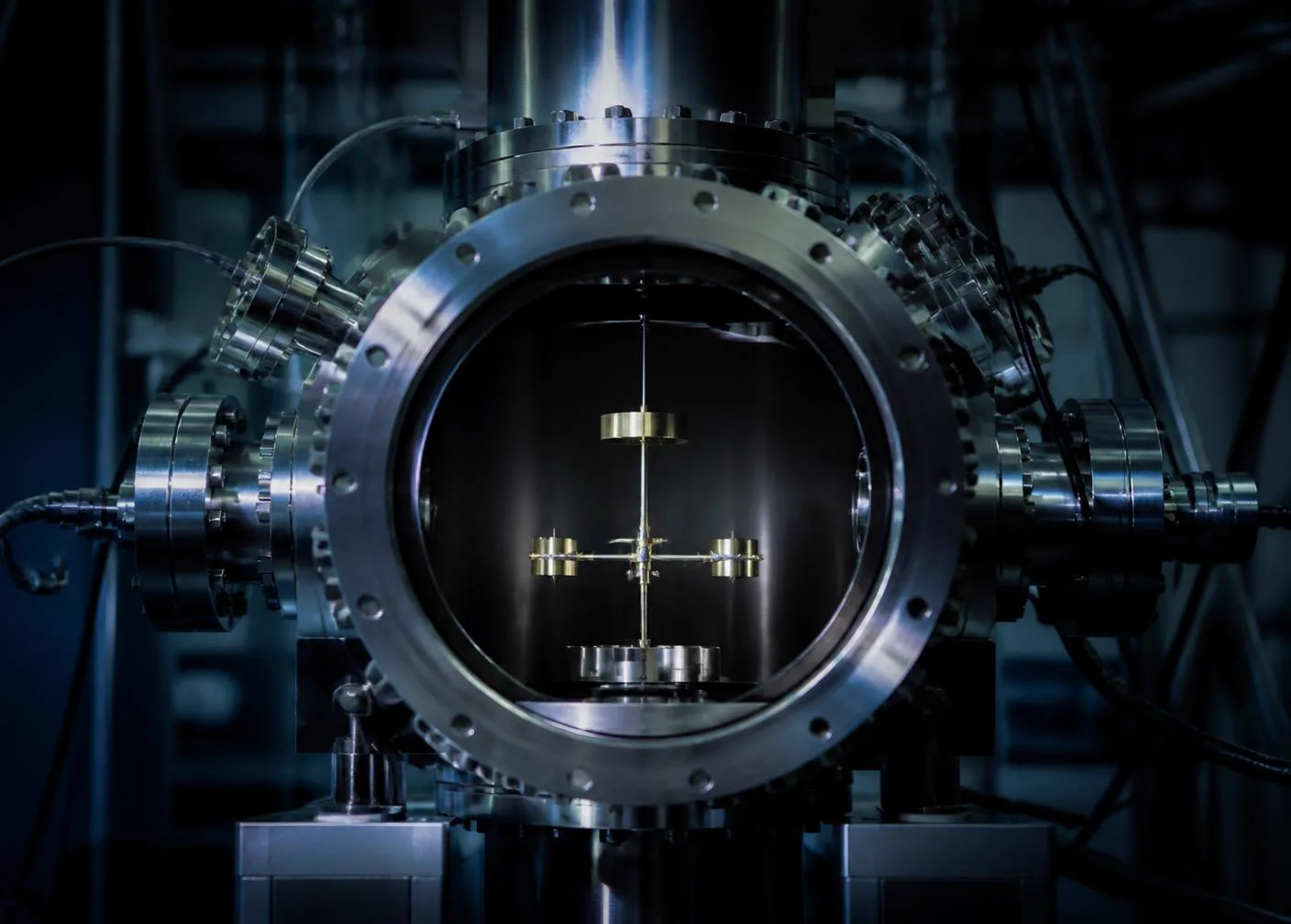 A torsion balance apparatus suspended inside a stainless steel vacuum chamber in a laboratory